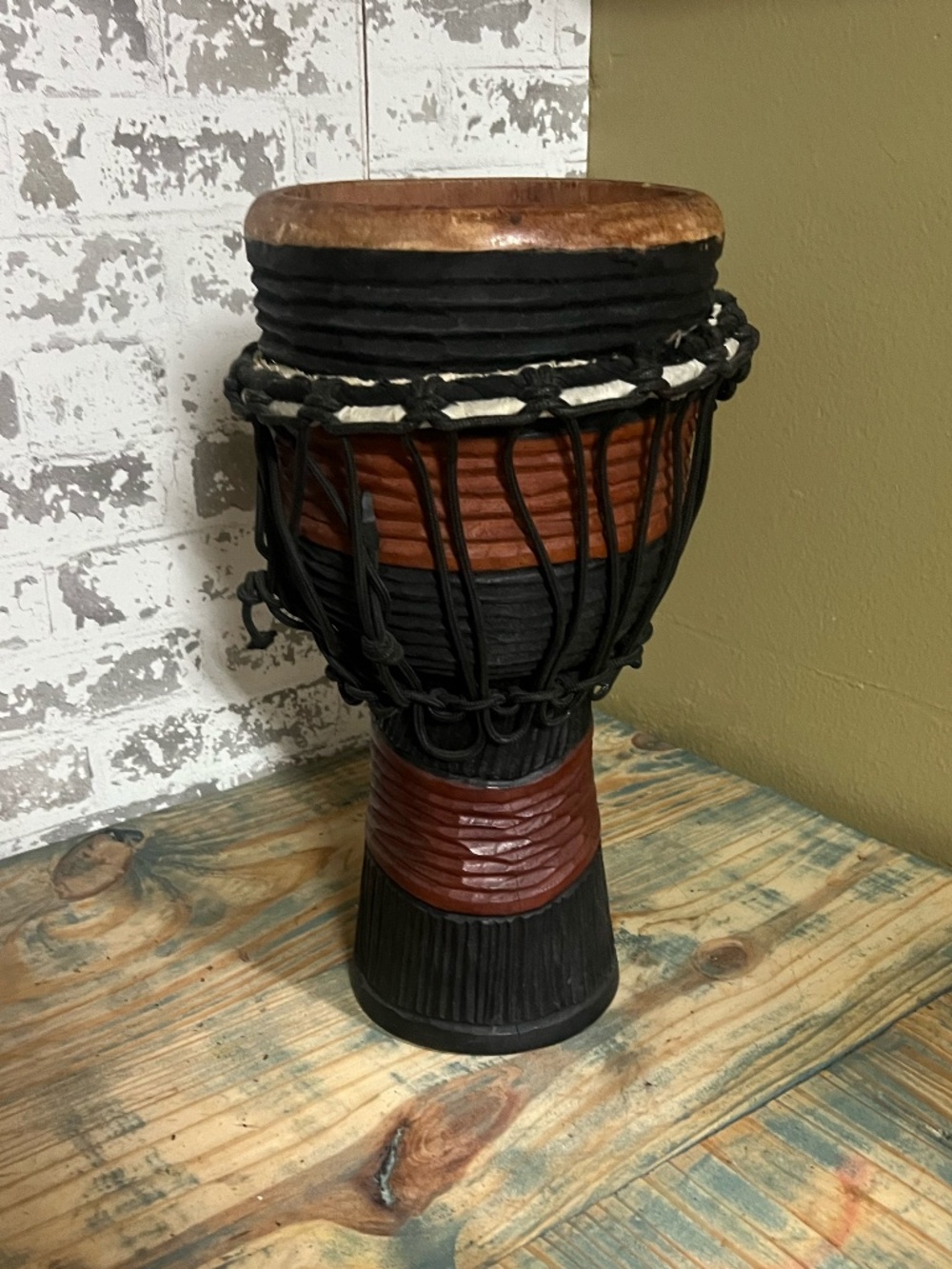 A brown Rope-tuned wooden djembe planter with black rope accents
